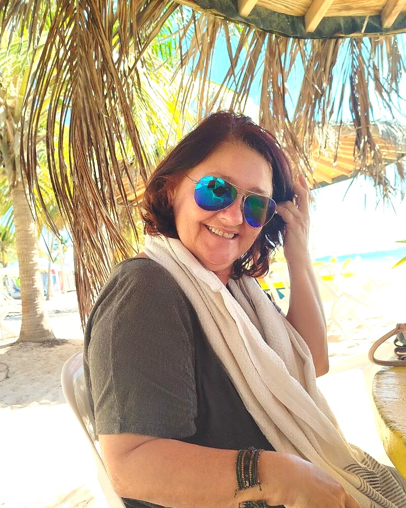 Nicole, fondatrice de Prestige Sitting, souriante sous un paillote en Guadeloupe